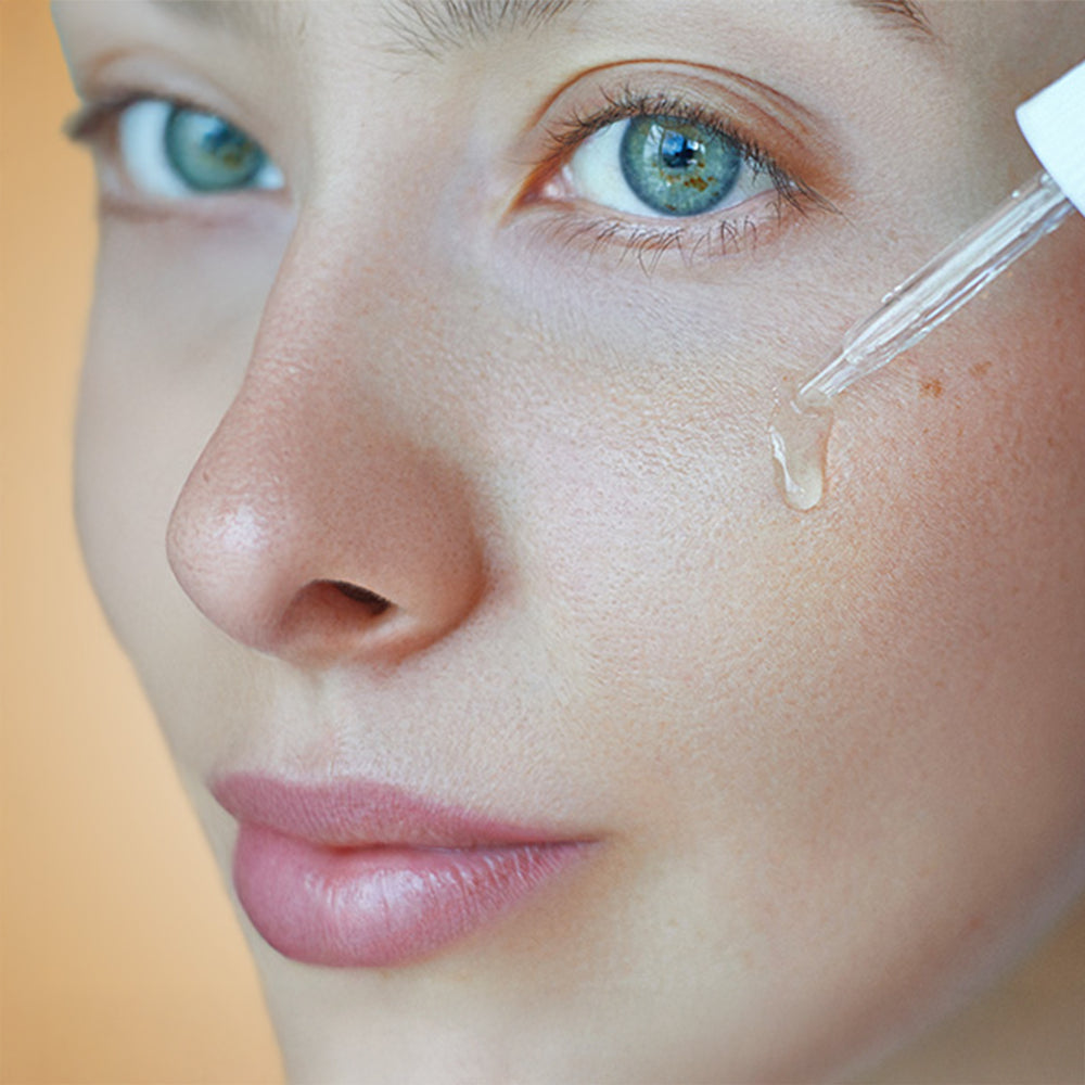 En kvinna applicerar HL/Skin Niacinamide Serum på sitt ansikte.